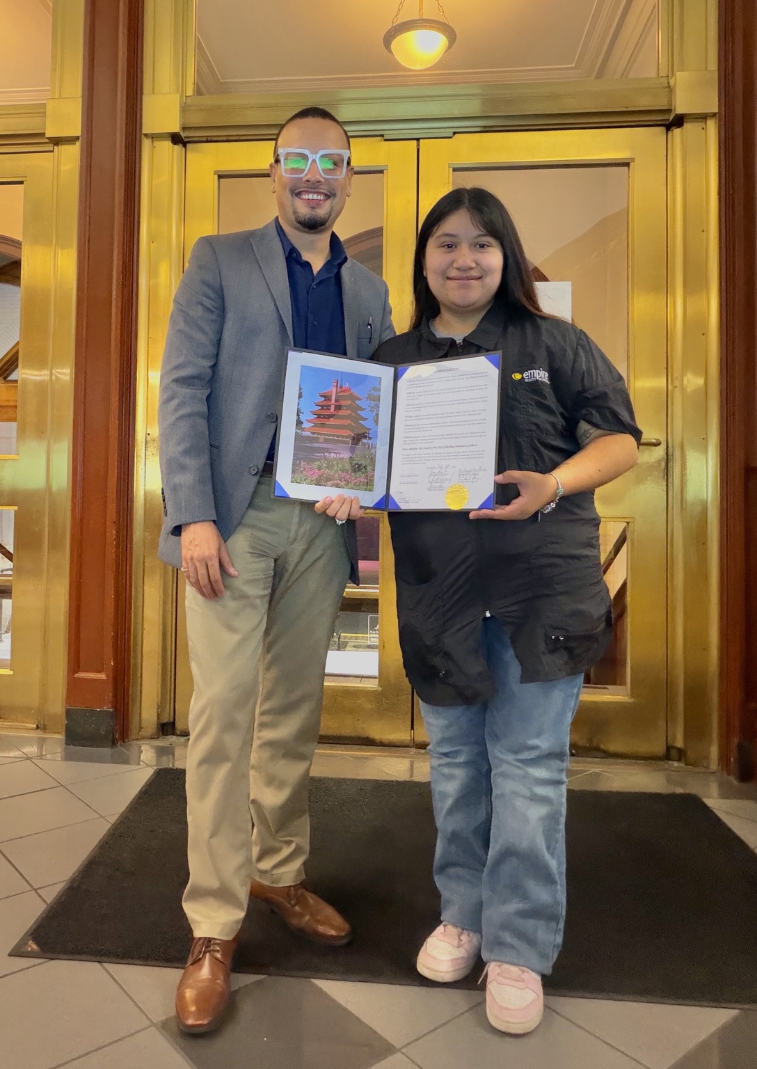 Jaime and a community member holding a recognition certificate