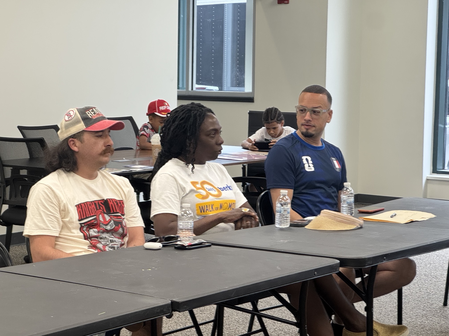 Jaime seated at a table listening as another participant speaks