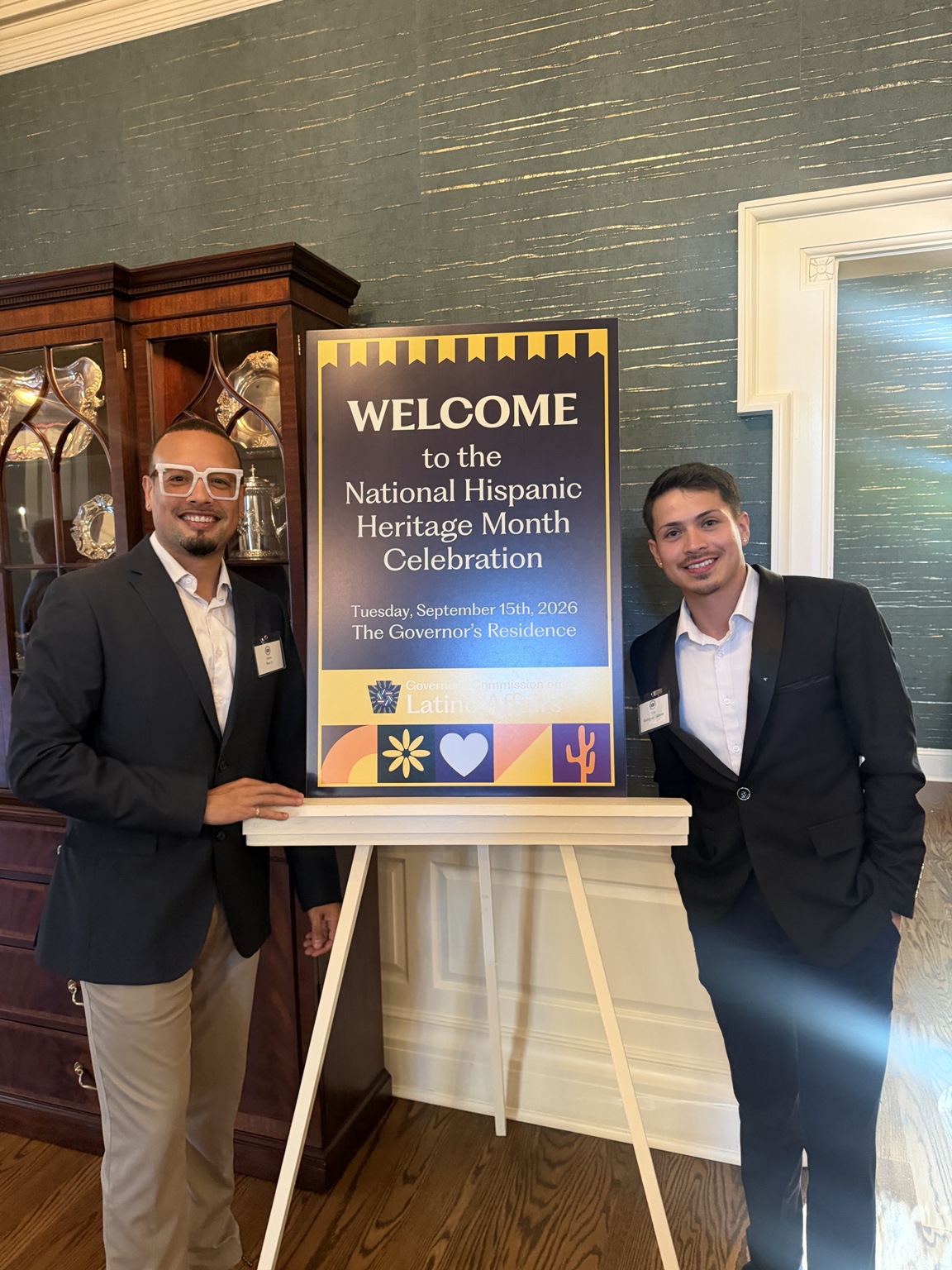 Jaime and another attendee beside the Hispanic Heritage Month celebration sign at the Governor’s Residence
