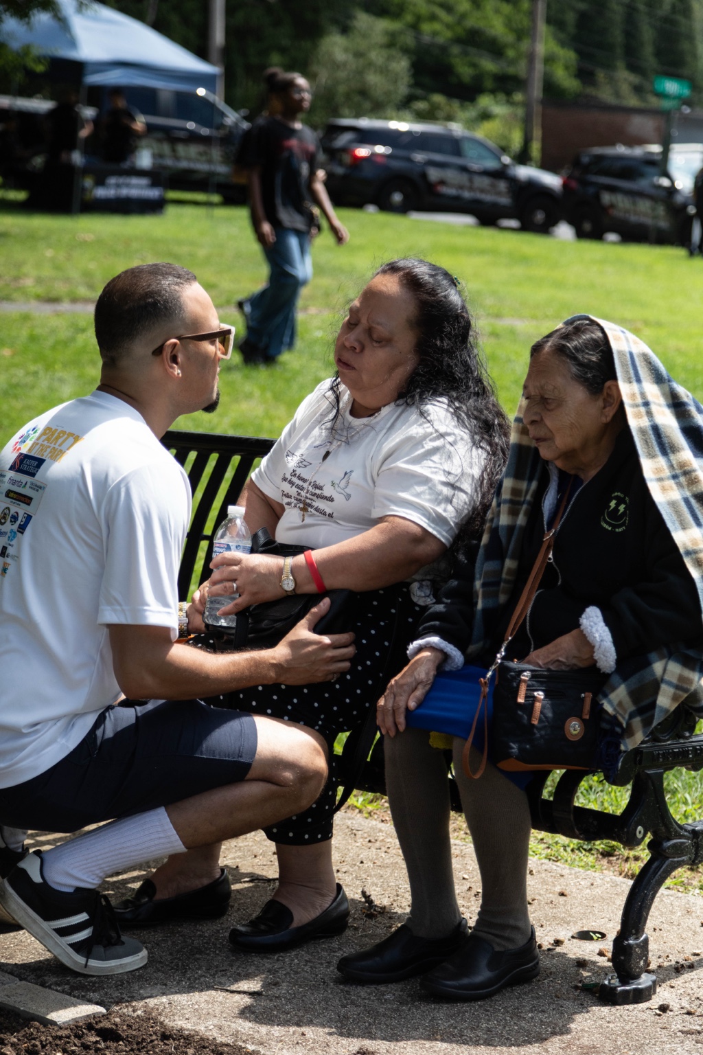 Jaime accompanying attendees seated on a park bench during the memorial brick dedication